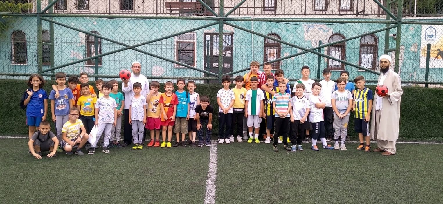 Sahada BUKED gönüllüleri ve bir grup çocuk top oynuyor