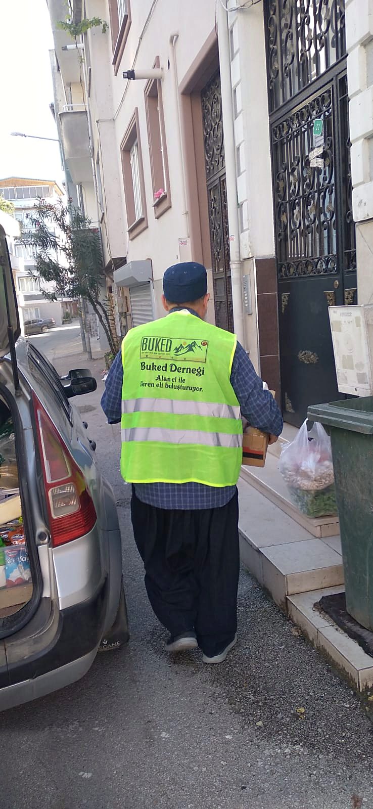 Bir gönüllü, yardım kolisini bir evin kapısına bırakıyor