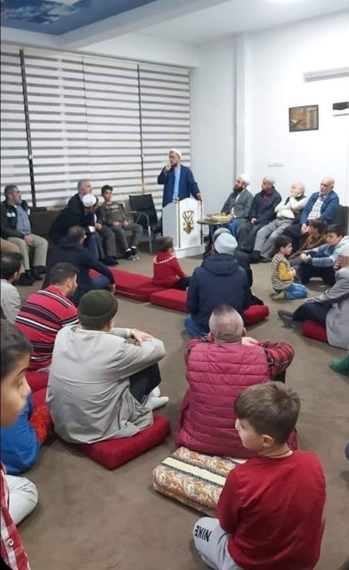 Sohbet salonunda yer minderlerinde oturmuş, kürsüdeki hocayı dinleyen bir cemaat